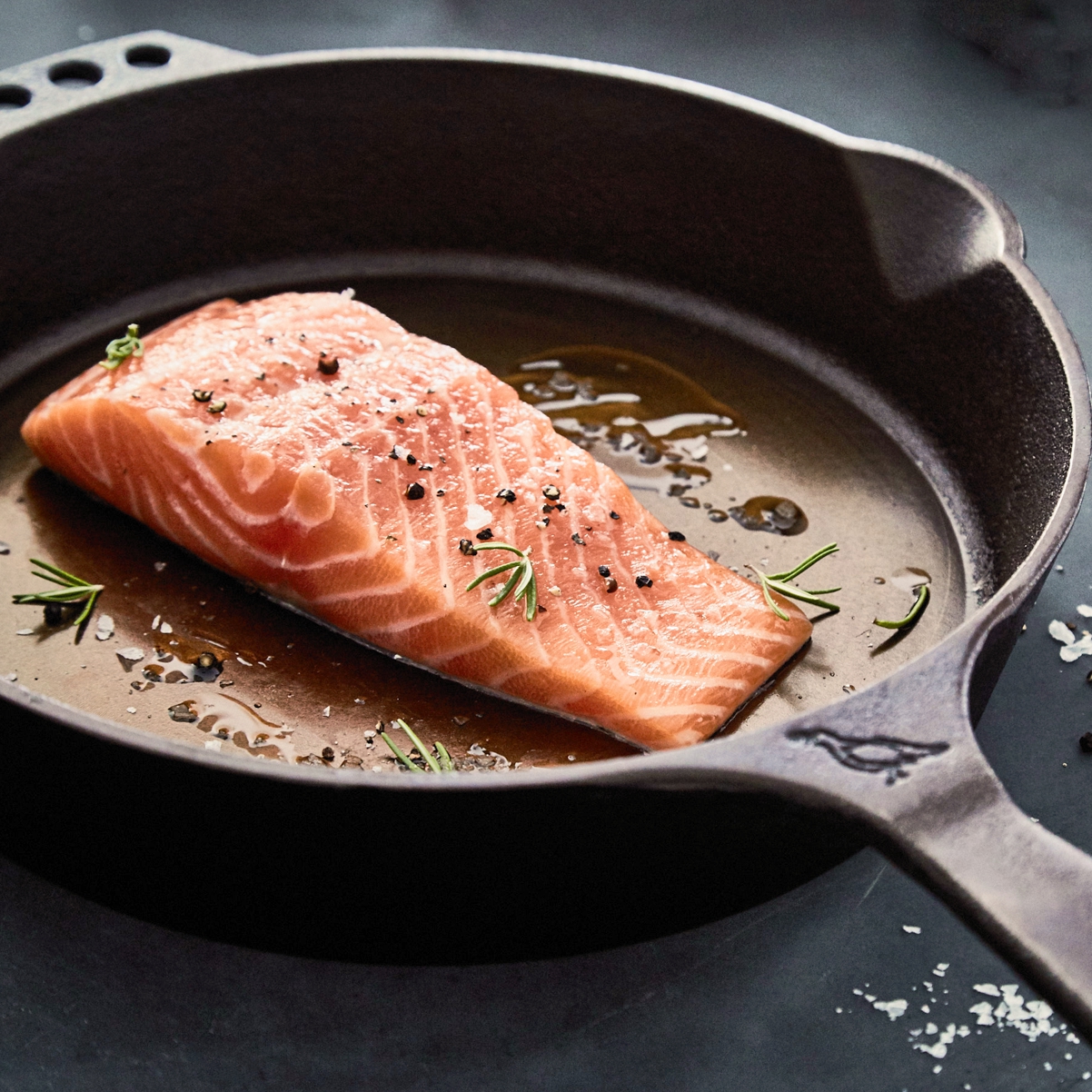 Salmon frying in cast iron skillet
