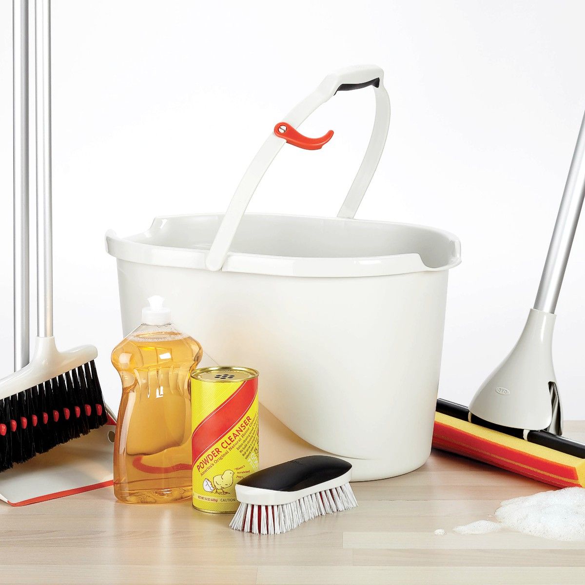 OXO Good Grips red, white, and black heavy duty scrub brush with cleaning supplies.