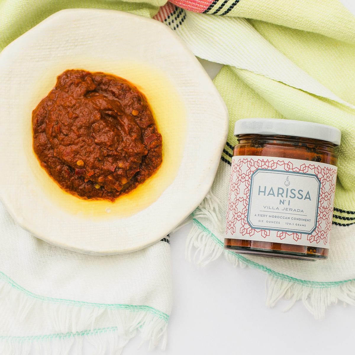 Villa Jerada jar of Harissa next to a plate of seasoned food