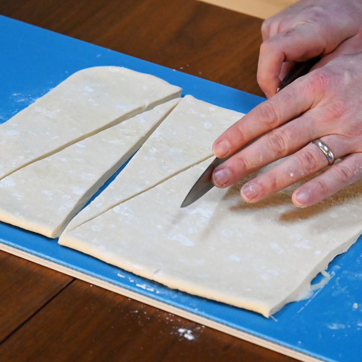 Cutting croissant triangles on blue board