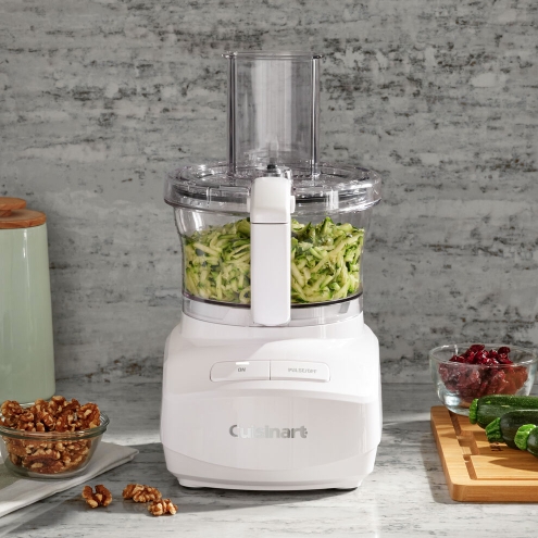 cuisinart white food processor on kitchen counter shredding zucchini