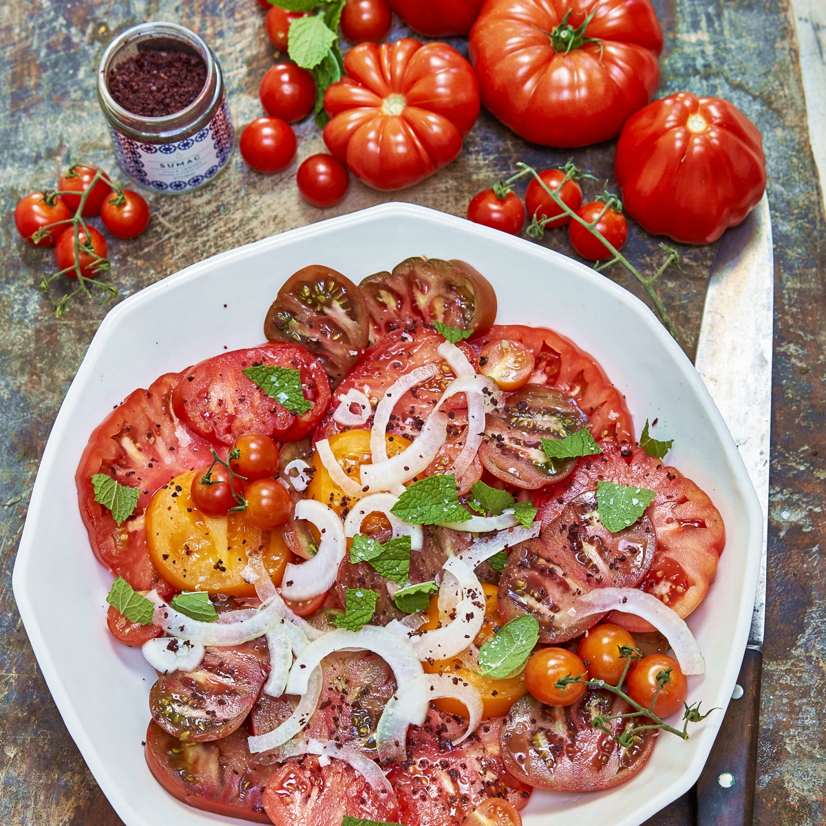 Sumac sprinkled over tomatoes and onions on plates