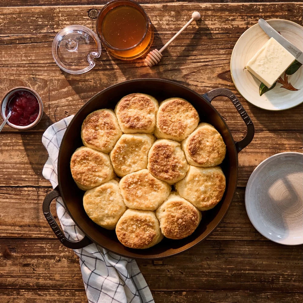 smithey dual skillet on wooden table full of homemade biscuits