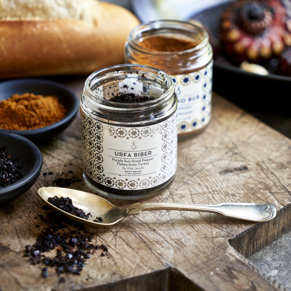 Spoonful of Urfa Biber next to an open jar of the spice