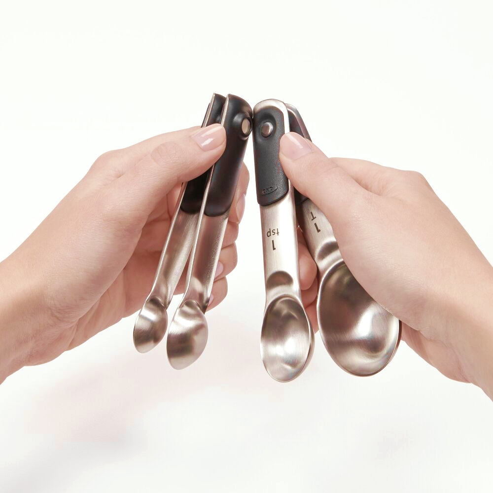 two hands holding oxo magnetic measuring cups
