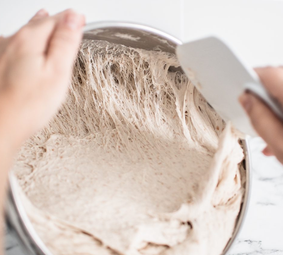 Scraping dough from bowl with hand spatula