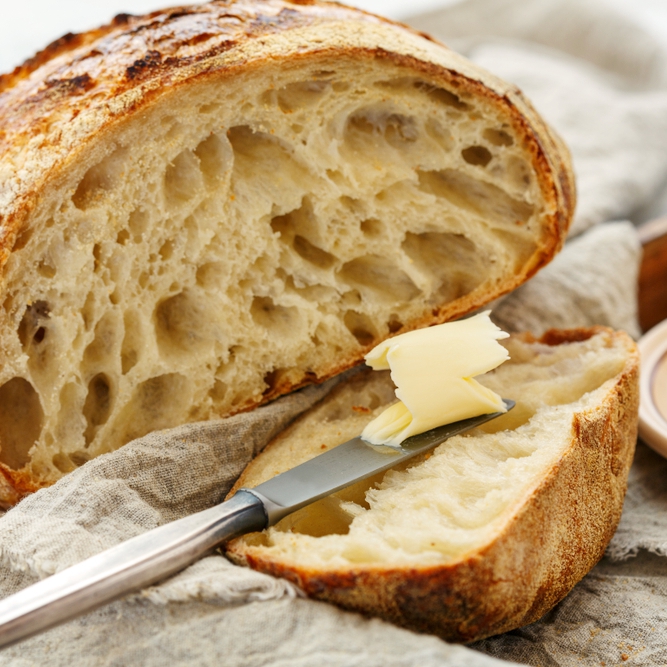 loaf of sourdough bread with butter and knife
