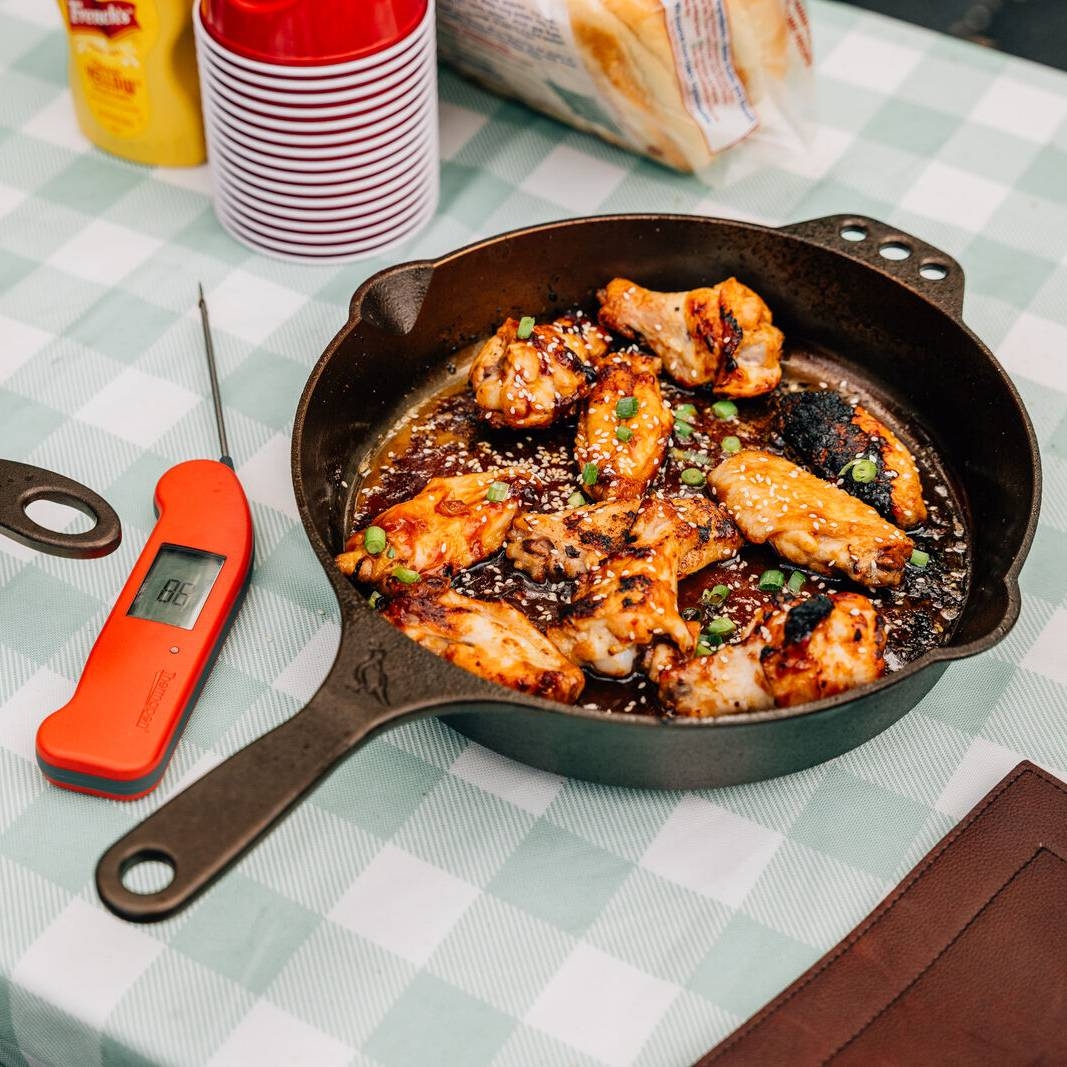 Chicken wings in 10 inch skillet on picnic table spread