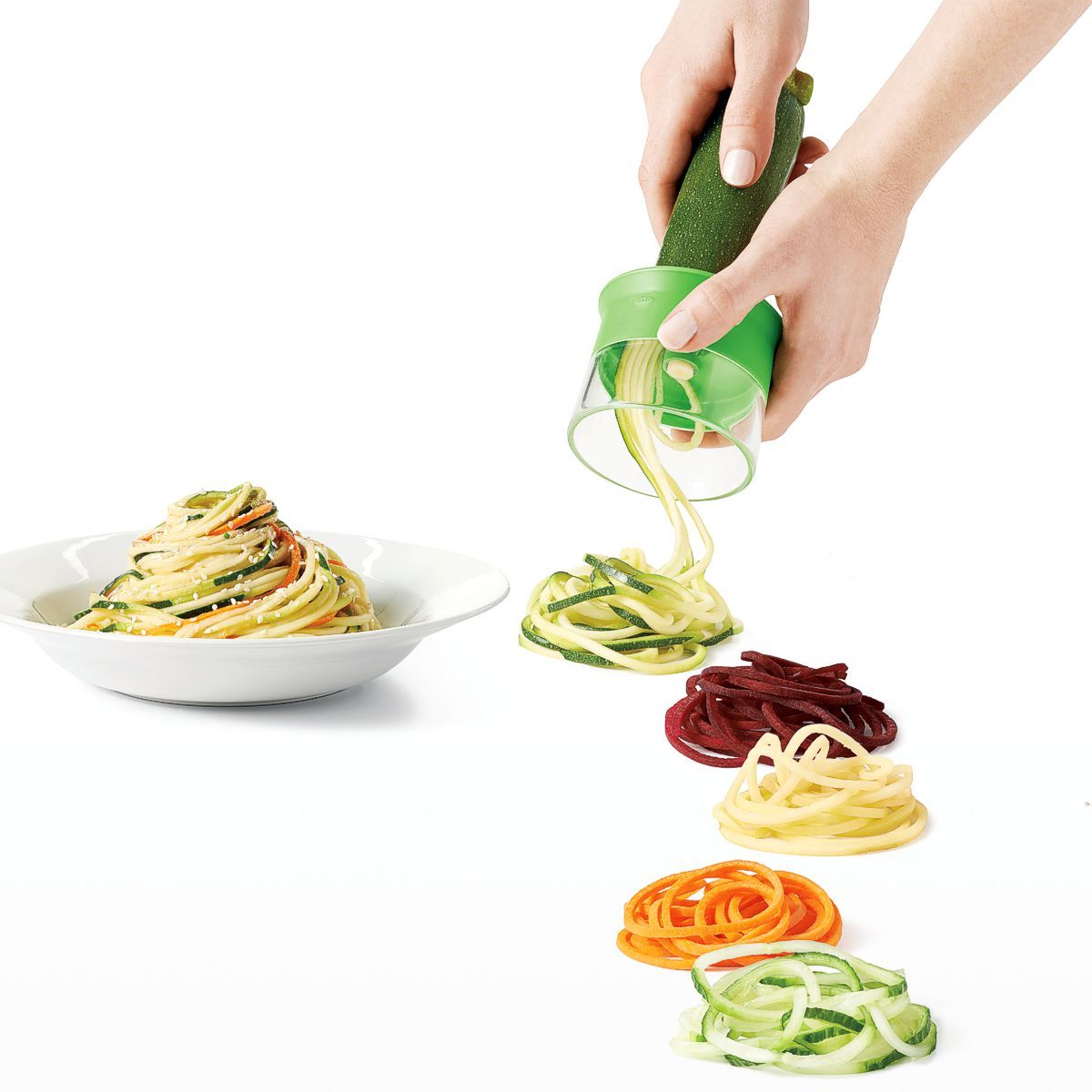 OXO Good Grips hand held spiralizer with piles of veggie noodles displayed.