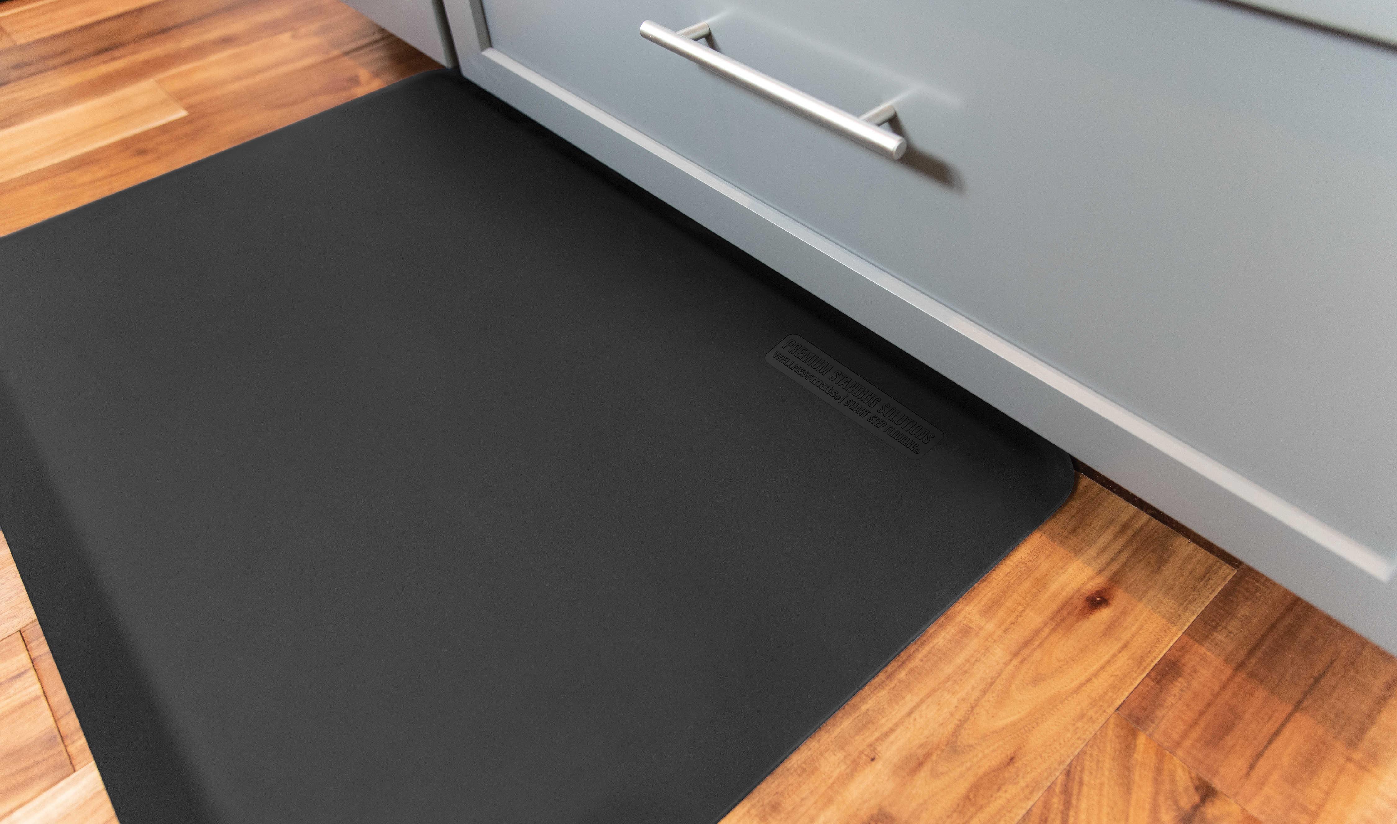 black wellness mat shown by gray cabinets and wood flooring