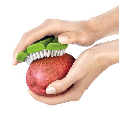 Green Cuisipro vegetable brush scrubbing potato.