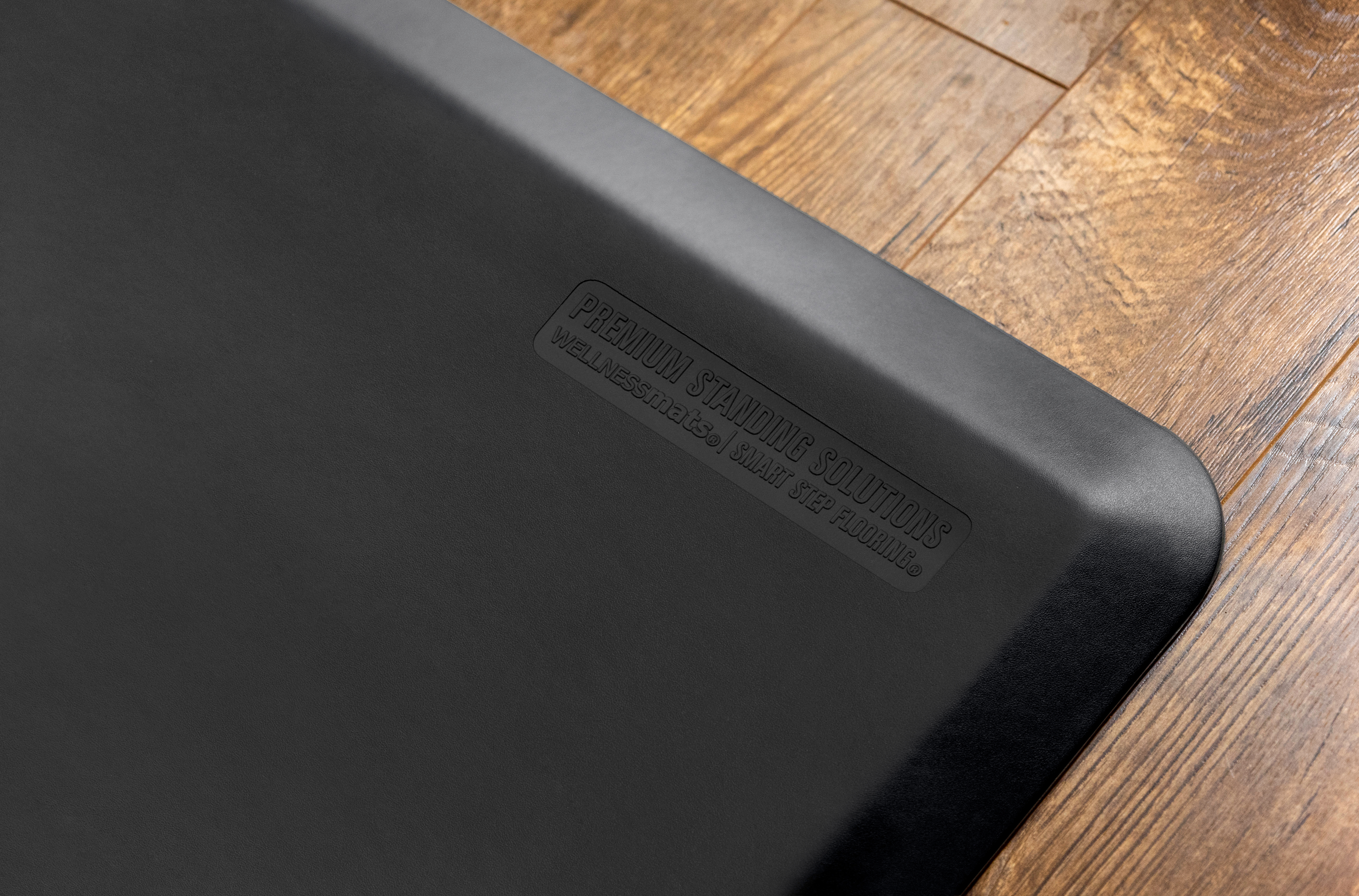 corner of black wellness mat on wood flooring
