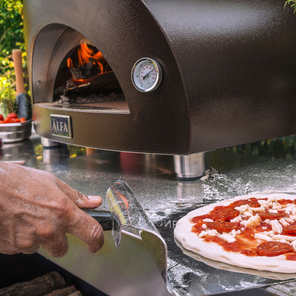 metal pizza peel transferring raw pizza into alfa pizza oven